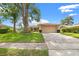 Inviting single-story home with a well-maintained lawn, mature trees, and an attached two-car garage at 3360 Masters Dr, Clearwater, FL 33761