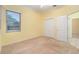 Bright bedroom with light yellow walls, neutral carpet, and closet with bi-fold doors at 3545 E Lake Dr, Land O Lakes, FL 34639