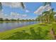 Expansive lake view from the grassy backyard with palms; a peaceful, waterfront property at 4811 Sandy Glen Way, Wimauma, FL 33598