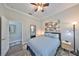 Cozy bedroom with an ensuite bathroom, queen-size bed, stylish decor, and gray wood floors at 4811 Sandy Glen Way, Wimauma, FL 33598
