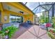 Inviting screened lanai with wicker furniture, ceiling fan, brick floors and relaxing lake view at 4811 Sandy Glen Way, Wimauma, FL 33598