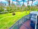 Expansive, well-manicured backyard with mature trees, viewed from a screened-in patio with brick flooring at 5454 Saddlebrook Way # 2, Wesley Chapel, FL 33543