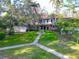 Two-story home with a manicured front yard featuring a sidewalk, well-maintained lawn, flowering shrubs, and mature trees at 5454 Saddlebrook Way # 2, Wesley Chapel, FL 33543