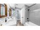 Modern bathroom with a double vanity, tile shower, and wood-framed mirrors, creating a luxurious and functional space at 6511 Senegal Palm Way, Apollo Beach, FL 33572