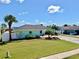 Beautiful front yard of a light blue home featuring well maintained landscaping and a brick driveway at 6511 Senegal Palm Way, Apollo Beach, FL 33572
