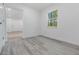 Bright bedroom features modern flooring, white walls, and a window overlooking the landscape at 7249 Berry Rd, Zephyrhills, FL 33540