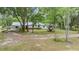 A charming house with a metal roof and ample yard space surrounded by lush greenery at 7249 Berry Rd, Zephyrhills, FL 33540