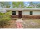 Close up of the front of the house, with a brick base, white siding and a stepping stone walkway at 7249 Berry Rd, Zephyrhills, FL 33540