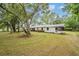 Charming one-story home with large front yard featuring mature trees and a screened in porch at 7249 Berry Rd, Zephyrhills, FL 33540