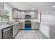 Modern kitchen featuring stainless steel appliances, gray cabinetry, and stone countertops at 7249 Berry Rd, Zephyrhills, FL 33540