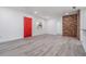 Bright and airy living room with brick accent wall and new flooring with a red door in the corner at 7249 Berry Rd, Zephyrhills, FL 33540