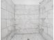 The renovated walk-in shower boasts elegant marble-look tiling and modern fixtures at 7249 Berry Rd, Zephyrhills, FL 33540