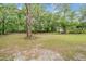 Spacious backyard with lush green grass and mature trees, providing ample shade at 7249 Berry Rd, Zephyrhills, FL 33540