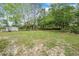 Large grassy backyard surrounded by mature trees offering privacy and a shed at 7249 Berry Rd, Zephyrhills, FL 33540