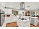 Modern kitchen with white cabinets, stainless steel appliances, island cooktop, and hardwood floors at 7591 Harbor View Way, Seminole, FL 33776