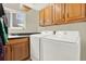 Laundry room with washer, dryer, sink, and wooden cabinets at 7591 Harbor View Way, Seminole, FL 33776