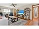 Comfortable living room with wood floors, ceiling fan, TV, and decoratively styled shelves at 7591 Harbor View Way, Seminole, FL 33776