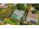 Aerial view of a home featuring a screened-in pool, lush landscaping, and a well-maintained roof at 838 Park Ct, Palm Harbor, FL 34683
