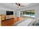 A primary bedroom with a ceiling fan, hardwood floors, and sliding glass doors leading to the screened in pool at 838 Park Ct, Palm Harbor, FL 34683