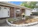 Close-up of the inviting front porch featuring brick accents, a beautifully decorated entryway, and charming landscaping at 9414 Northcliffe Blvd, Spring Hill, FL 34606