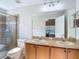 Bathroom featuring a double sink vanity, toilet, and a glass enclosed shower at 9608 Rolling Cir, San Antonio, FL 33576