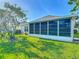 Exterior view of sunroom surrounded by a lush green lawn, complemented by mature trees and well-maintained landscaping at 9608 Rolling Cir, San Antonio, FL 33576