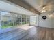 Bright sunroom with wood floors and large windows offering plentiful sunlight, ceiling fan and dart board included at 9608 Rolling Cir, San Antonio, FL 33576