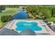 Aerial view of a uniquely shaped pool with lounge chairs, umbrellas, and swimmers, highlighting the community's recreational amenities at 9608 Rolling Cir, San Antonio, FL 33576