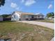 Front exterior of a white single story home with tan trim, a driveway, and lawn on a sunny day at 10968 105Th Ave, Largo, FL 33778