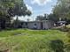 Rear exterior view of home featuring an exterior door, grass lawn and lush mature trees at 1204 E Camellia Dr, Brandon, FL 33510