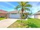 Charming single-story home with a well-manicured lawn and a beautiful palm tree in the front yard at 1666 Meadow Oak Ln, Tarpon Springs, FL 34689