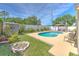 Backyard featuring a pool, a fire pit, a storage shed, and a white fence at 1666 Meadow Oak Ln, Tarpon Springs, FL 34689