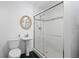 Bathroom featuring a sliding glass shower, pedestal sink, round mirror, and tile floors at 1720 Emerald Dr, Clearwater, FL 33756