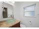 Bathroom featuring a sleek glass bowl sink, granite countertop, wood cabinet and a frosted window at 1720 Emerald Dr, Clearwater, FL 33756