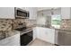 Modern kitchen with stainless steel appliances, white cabinets, and view of the outdoor landscape at 2017 Skimmer W Ct # 416, Clearwater, FL 33762