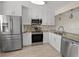 Modern kitchen with stainless steel appliances, white cabinets, and grey and white backsplash at 2017 Skimmer W Ct # 416, Clearwater, FL 33762