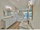 Modern bathroom features double vanities, soaking tub, a walk-in shower, and wood-look tile floors at 4804 Longwater Way, Tampa, FL 33615
