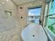 The bathtub is the focal point of this bathroom with marble-look tile, a shower, and hexagon tile flooring at 4804 Longwater Way, Tampa, FL 33615