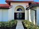 Elegant home featuring a Spanish tile roof, an arched entryway, and lush, tropical landscaping at 4804 Longwater Way, Tampa, FL 33615