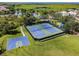 Aerial shot of community tennis and basketball courts surrounded by lush green fields near the water at 4804 Longwater Way, Tampa, FL 33615