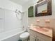 Clean bathroom featuring a shower-tub combo, pink sink, and decorative mirror at 5995 59Th N Way, St Petersburg, FL 33709