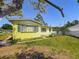 Side yard view of yellow house with green shutters, landscaping and sunny skies at 5995 59Th N Way, St Petersburg, FL 33709