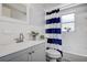 This bathroom features a blue and white striped shower curtain and a gray vanity at 7830 Judith Cres, Port Richey, FL 34668