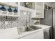 Modern kitchen featuring stainless steel sink, patterned backsplash, and white cabinetry at 818 37Th Ne Ave, St Petersburg, FL 33704