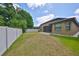 Large backyard, framed by a white fence, featuring green grass and a home with a screened patio at 838 Vino Verde Cir, Brandon, FL 33511