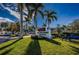 A beautiful shot of Boca Ciega Resort Condominium with lush landscaping and mature palm trees on a bright sunny day at 8800 Bay Pines Blvd # 303, St Petersburg, FL 33709