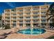 Resort-style pool surrounded by brick pavers, lounge chairs, and the condo building at 8800 Bay Pines Blvd # 303, St Petersburg, FL 33709