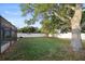Spacious backyard featuring a large tree, green grass, vinyl fence, and a screened-in pool at 10812 96Th St, Largo, FL 33773