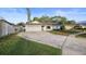 Single-story home featuring a long driveway, well-manicured lawn, white garage, and a charming pastel pink front door at 10812 96Th St, Largo, FL 33773