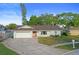 Inviting home with a tidy lawn, long driveway, a two-car garage, and a pink front door accentuating its curb appeal at 10812 96Th St, Largo, FL 33773